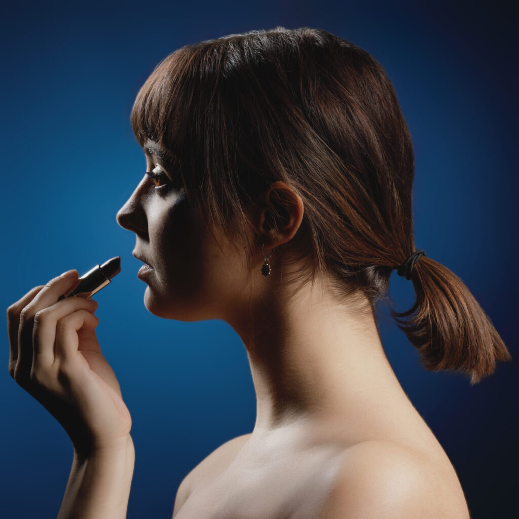 Mélina se maquille sur un fond bleu